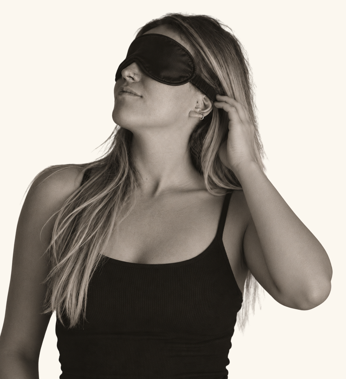 Woman wearing a sleep mask with her hand beside the strap