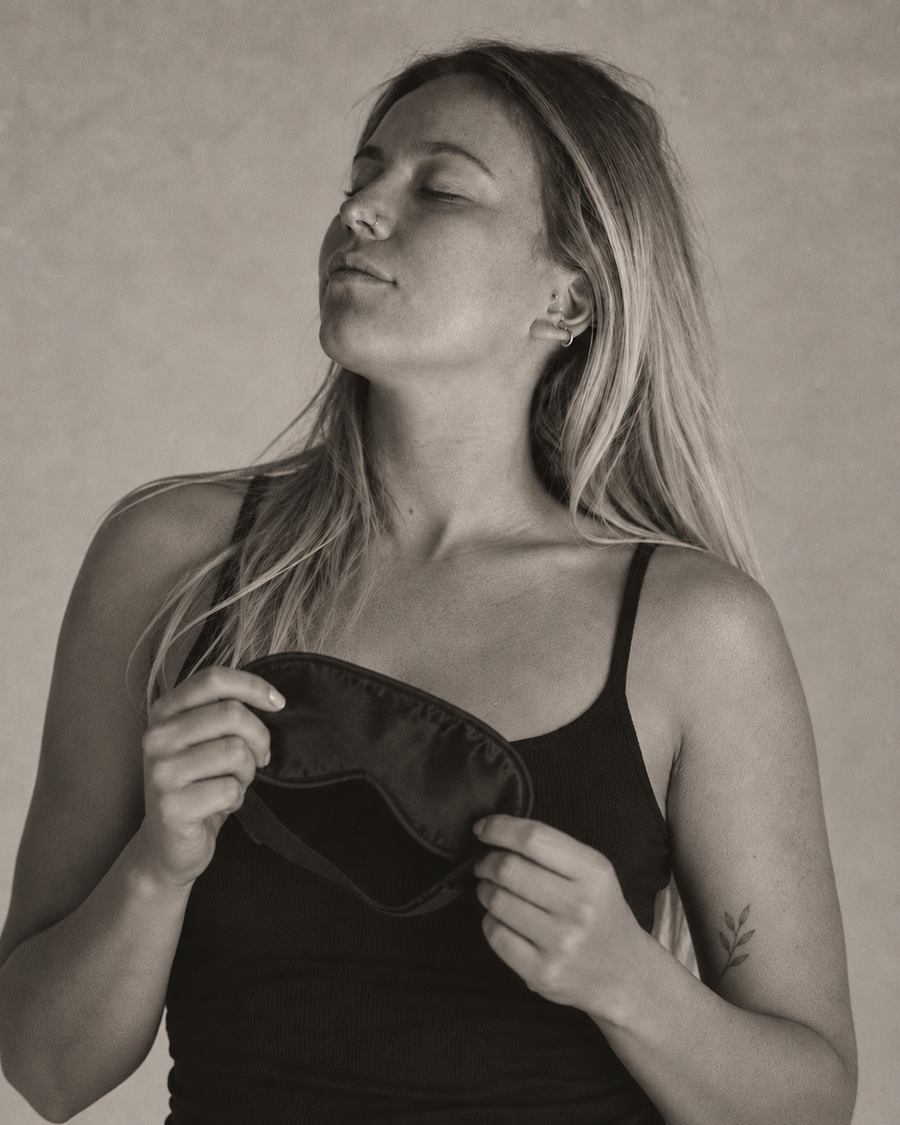 Woman holding a sleep mask with her eyes closed